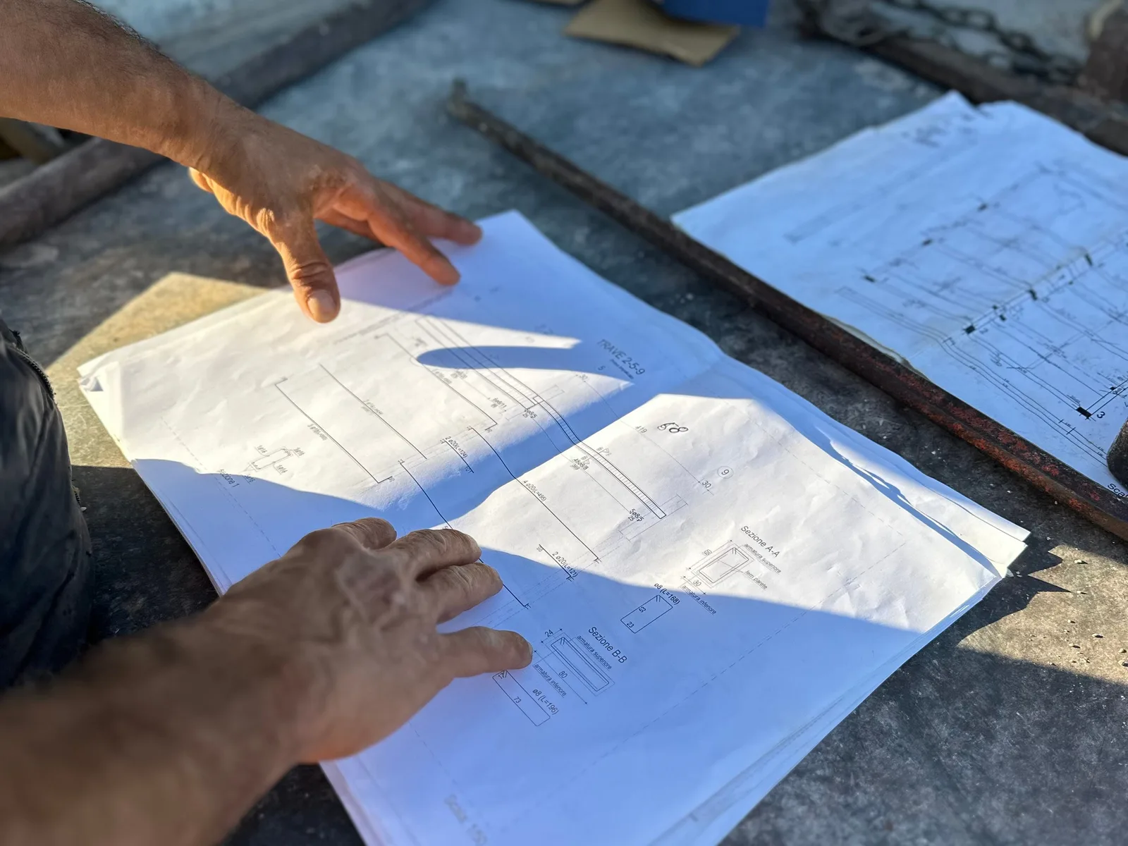 Şantiyede statik proje çizimlerini inceleyen eller